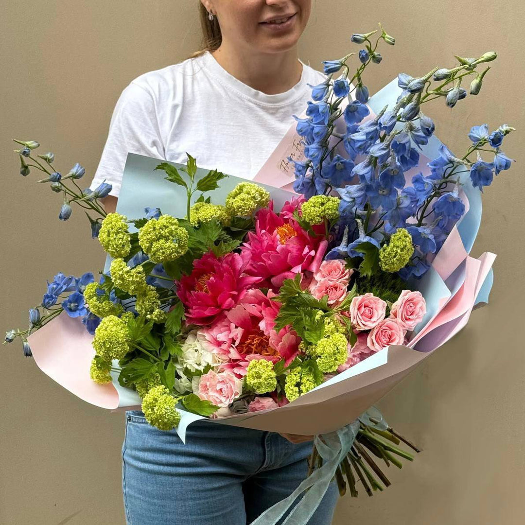 Person holding a colorful bouquet of flowers against a plain background