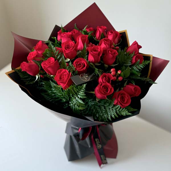 24 red roses, elegantly wrapped in black wrap.